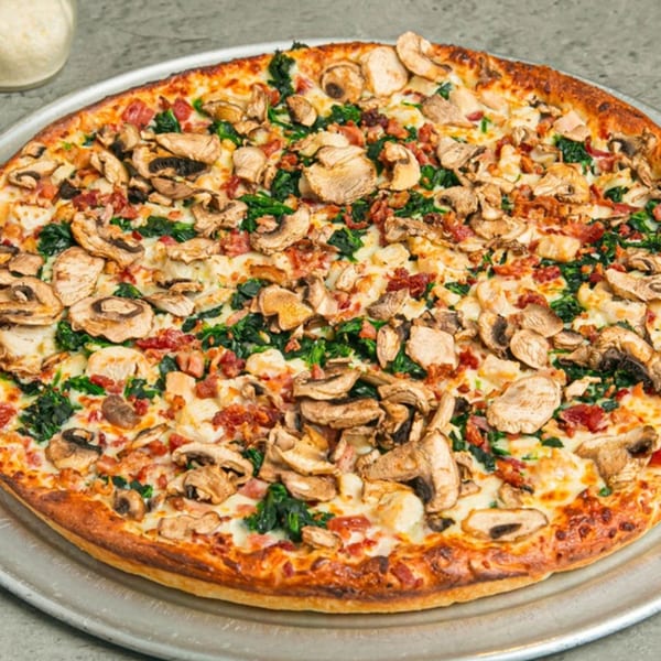 Lenzini's Pizza with mushrooms, spinach, and bacon on a metal tray.
