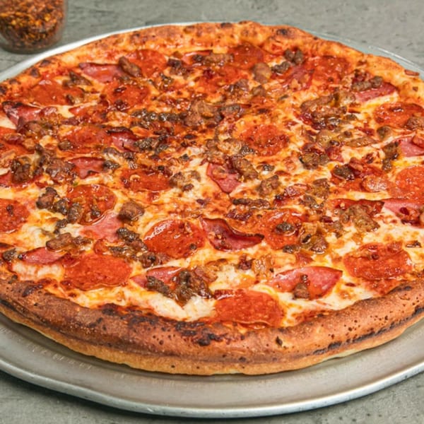 Lenzini's Pizza with pepperoni, sausage, and melted cheese on a metal tray.